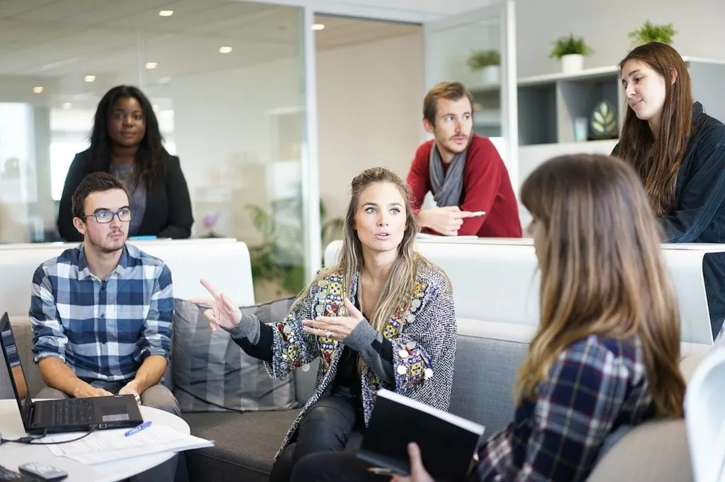 Employés qui discutent symbolisant la communication interpersonnelle au travail.