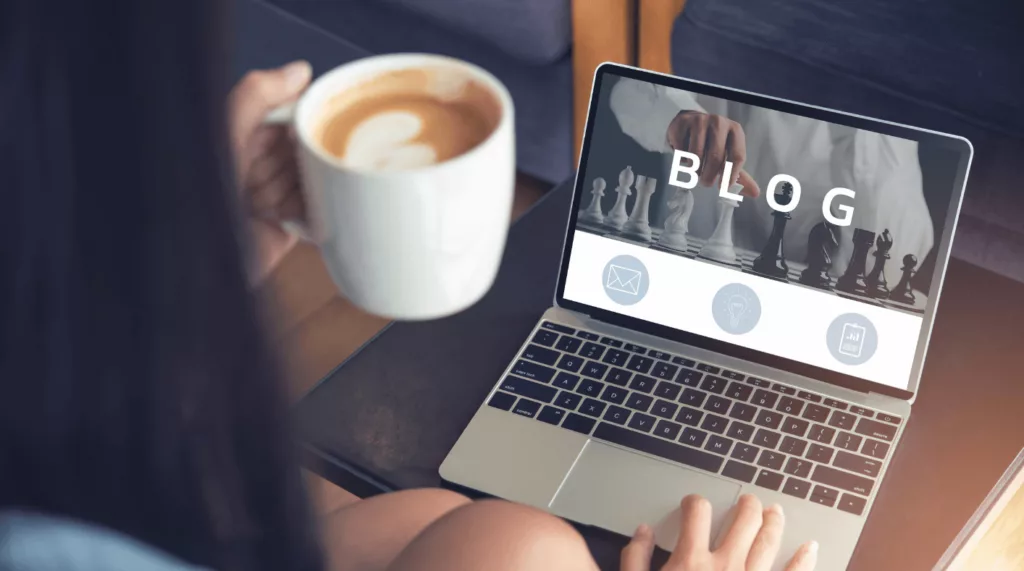 Femme qui boit un café devant les articles du blog de l'agence web.