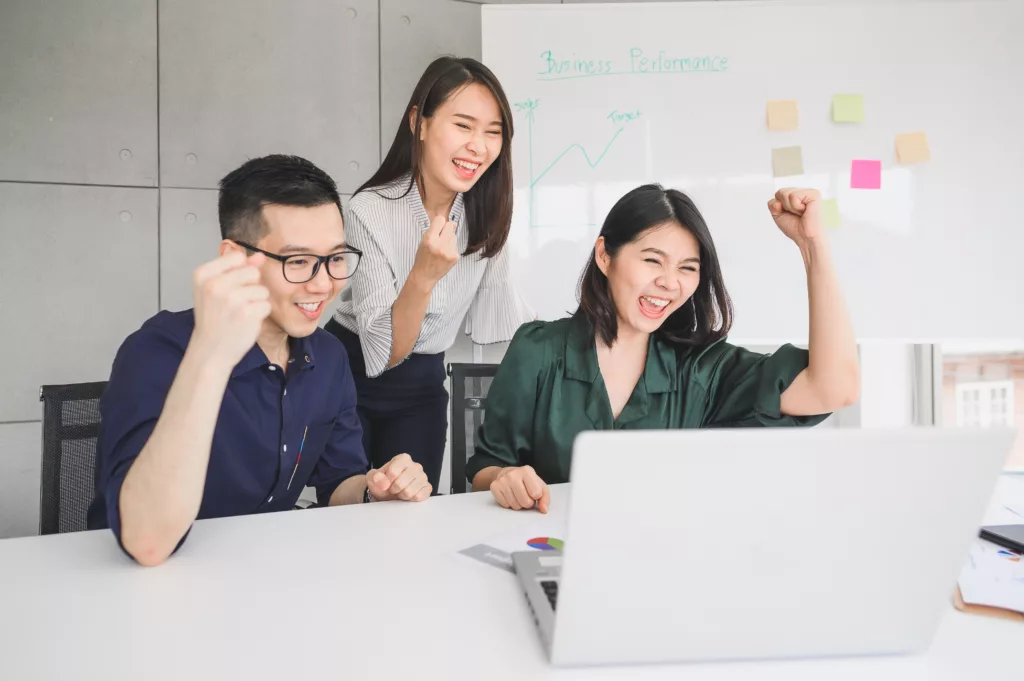 Equipe de travail heureuse symbolisant la collaboration lors de la gestion de projet.
